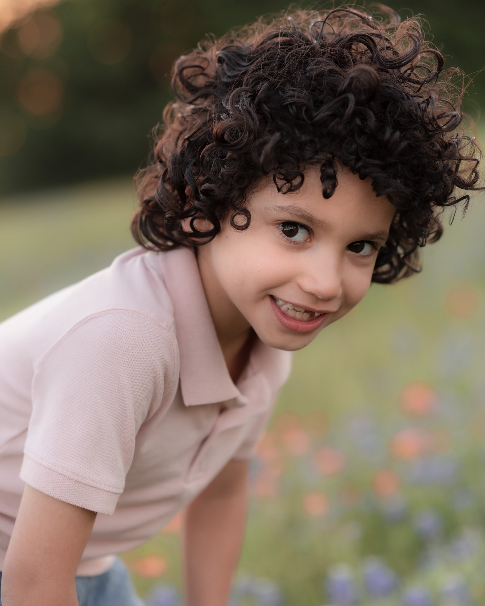 Teresa Vitela spring portrait - happy young boy in pink shirt surrounded by bluebonnets Bryan Texas
