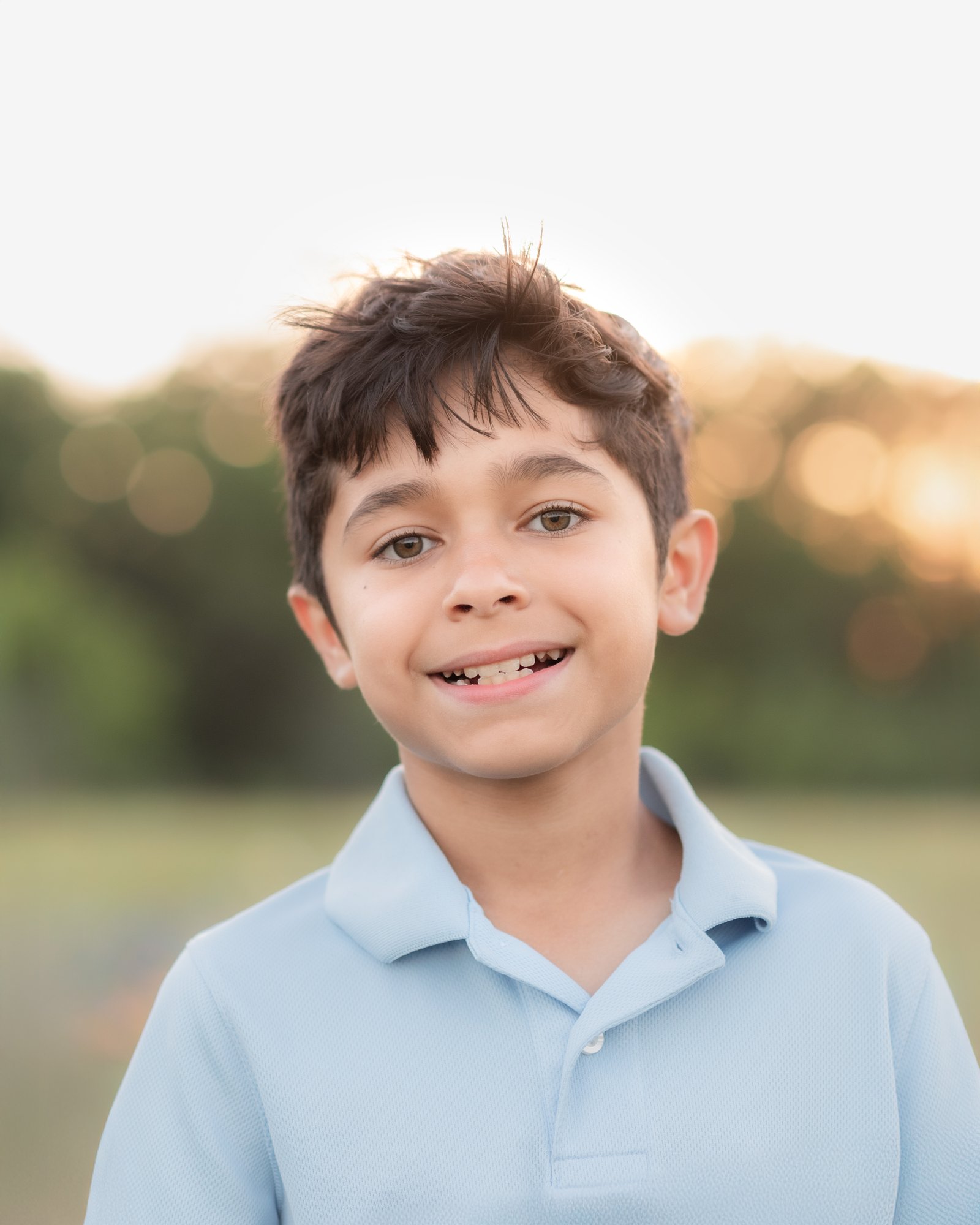 Teresa Vitela bluebonnet portrait - young boy in blue shirt smiling in Texas bluebonnet field Bryan College Station Texas