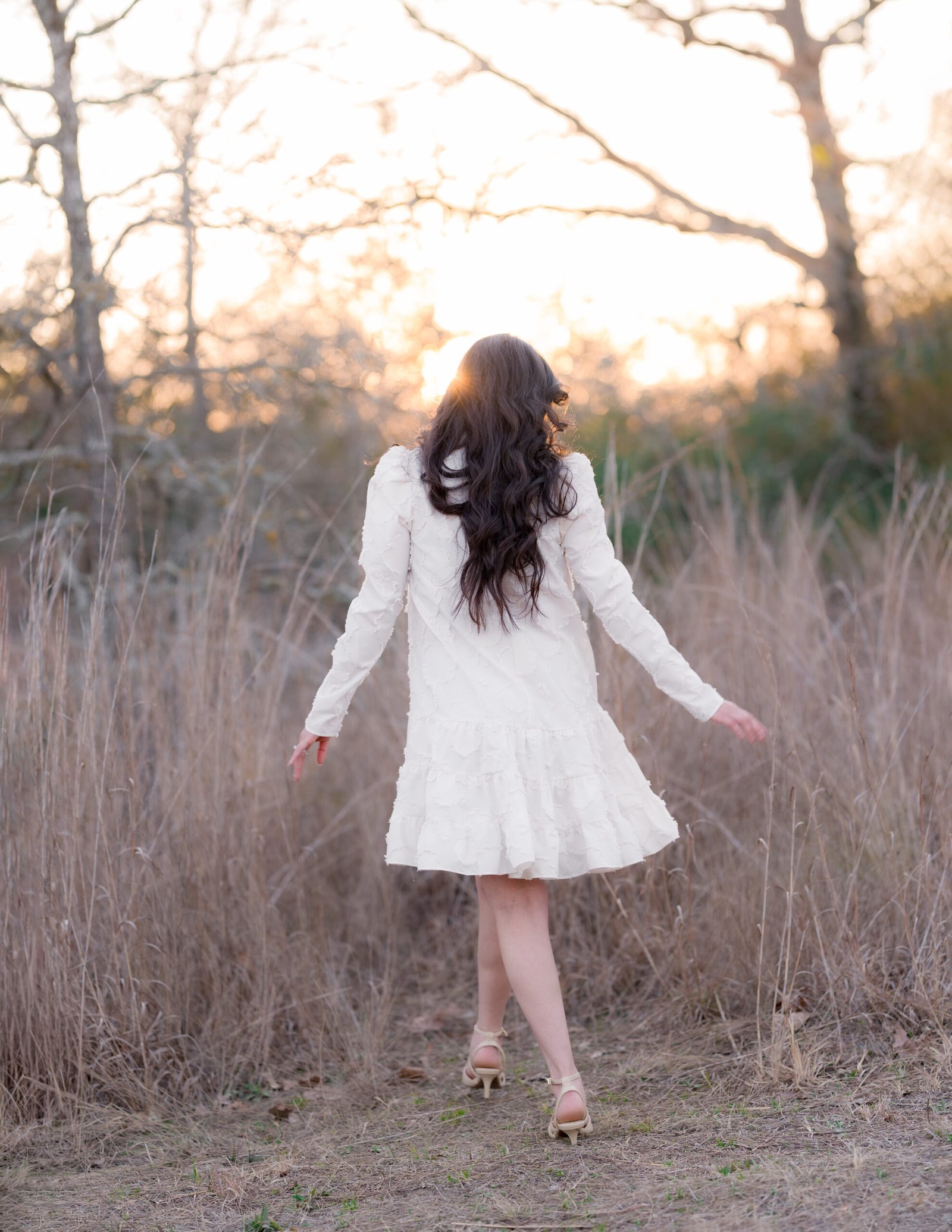 Teresa Vitela The Legacy - woman in white flowing dress walking toward golden light looking away open field Bryan College Station Texas