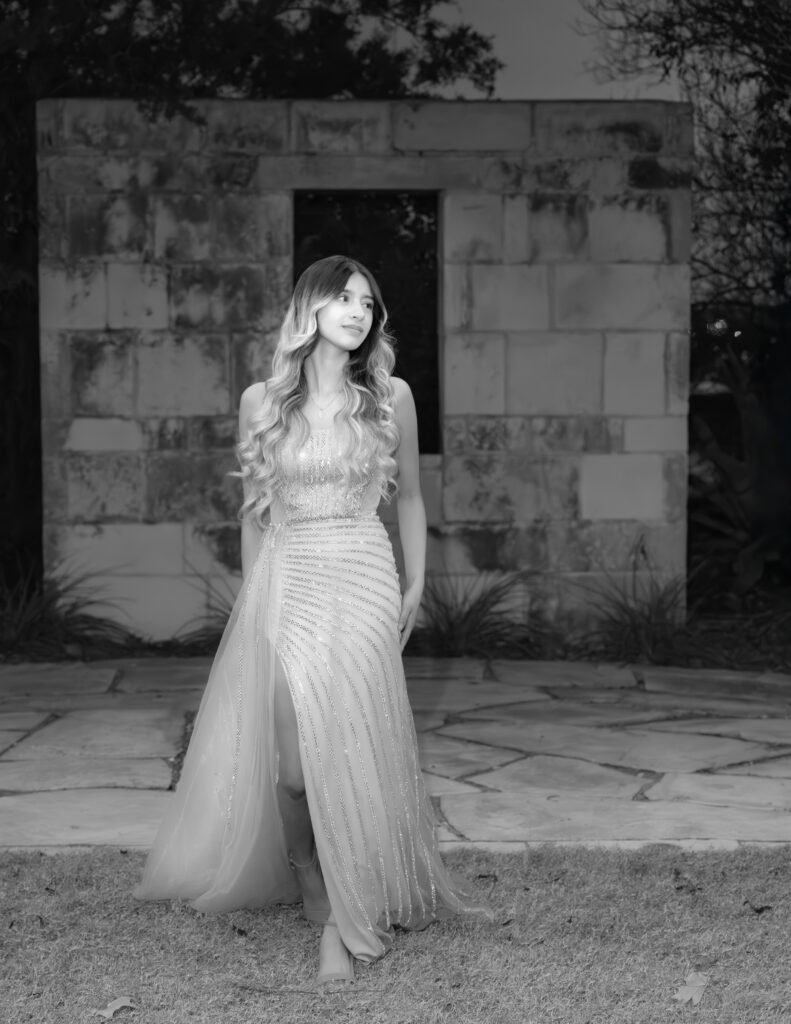 Luxury editorial black and white portrait of a woman in a beige gown against an ornate stone wall. Fine Art photography in Dallas, Texas.