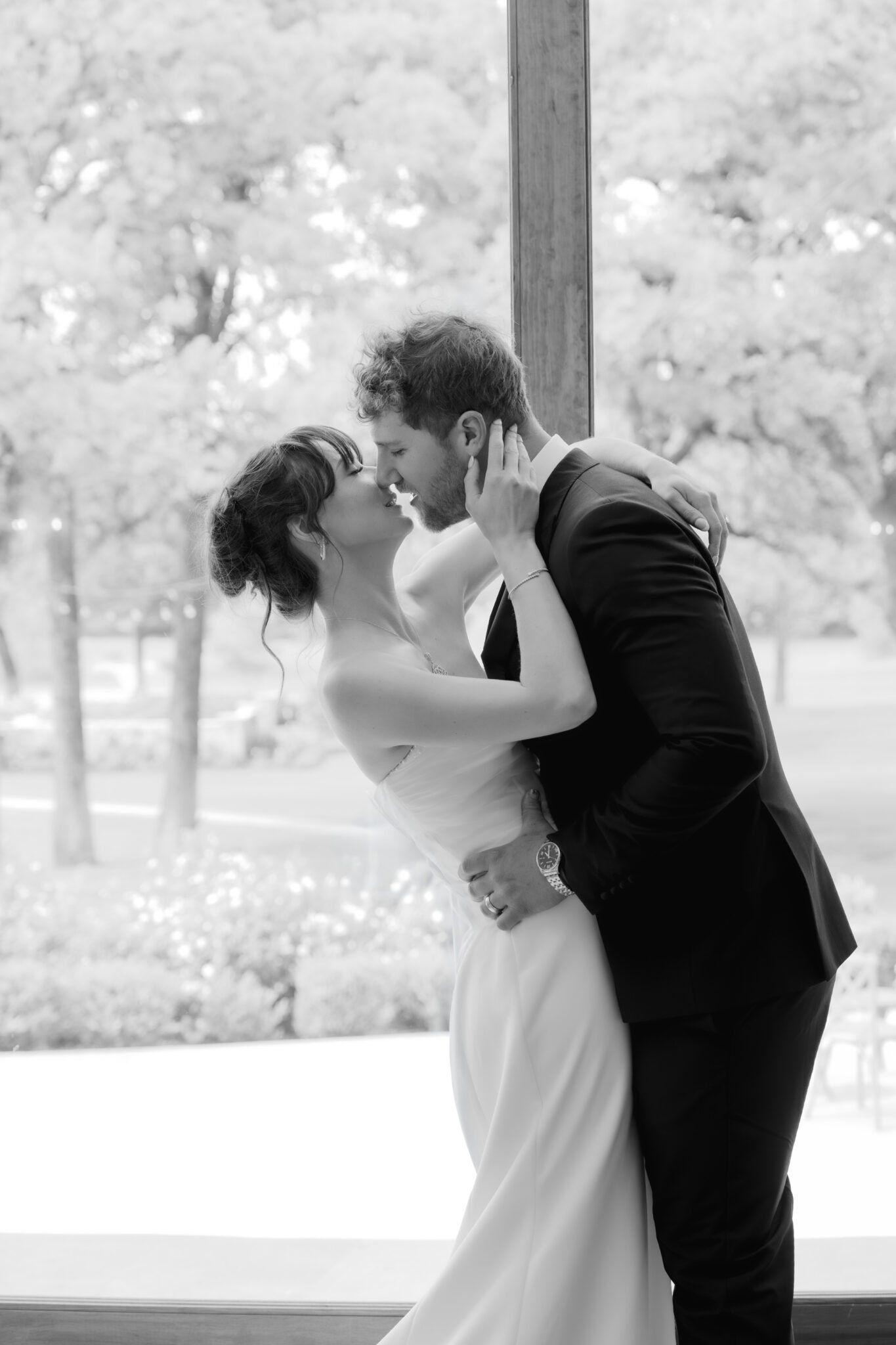 Artistic black and white close-up of a bride and groom sharing a romantic kiss.