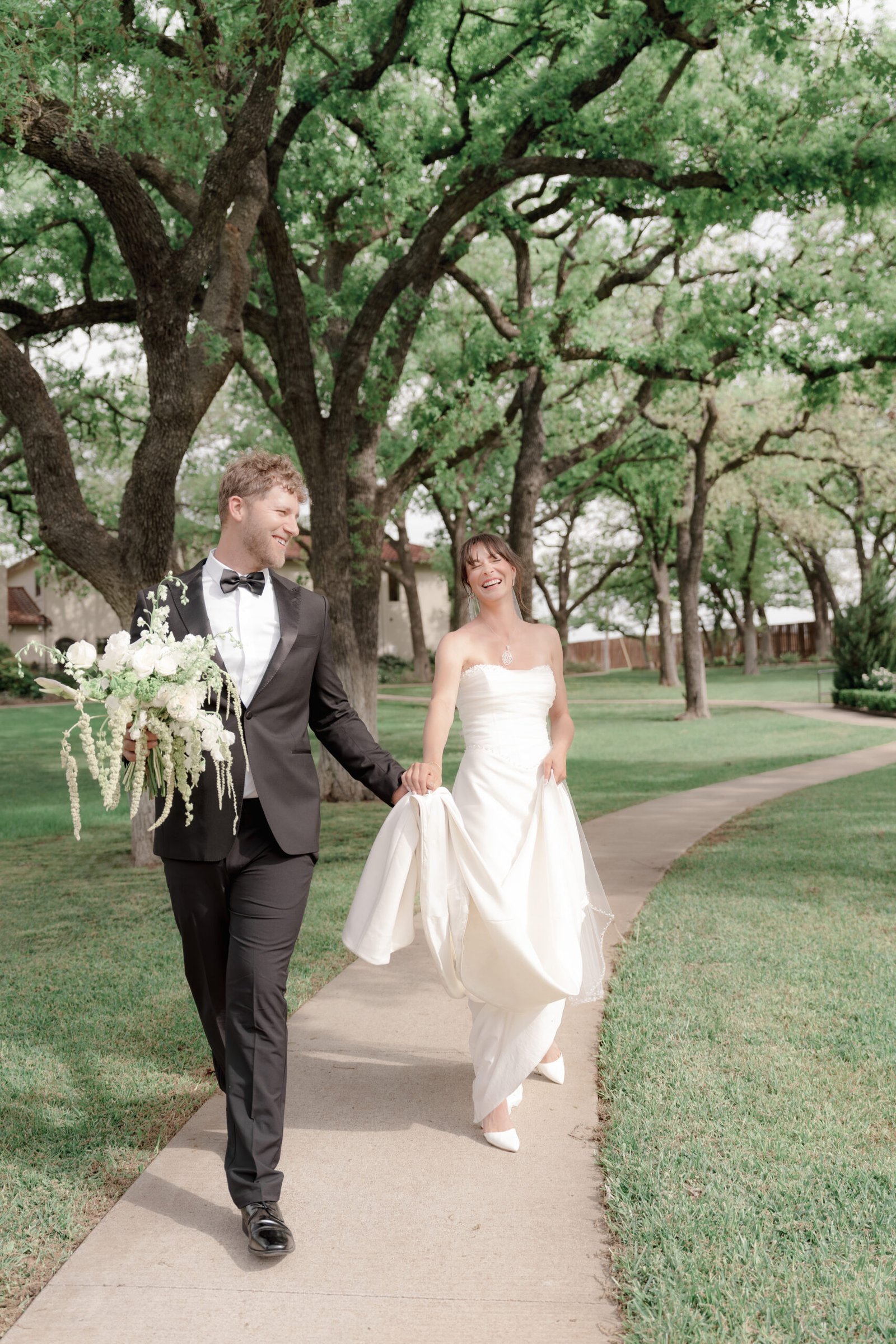 Candid editorial wedding photography of a bride and groom walking through a luxury estate garden in Texas.